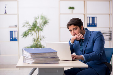 Young male employee and too much work in the office