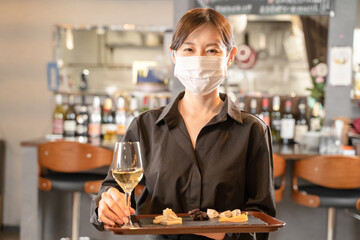 マスクで感染症対策して食事を提供する女性スタッフ