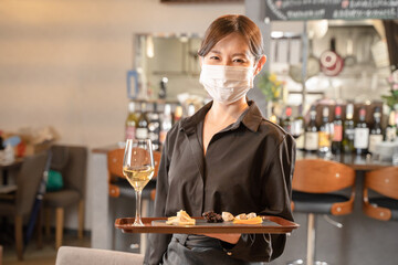マスクで感染症対策して食事を提供する女性スタッフ