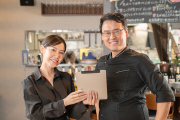 飲食店でタブレットPCで相談する男女の店員