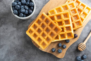 Stack of belgian waffles with blueberry and honey for breakfast. Delicious homemade pastry. Copy space.