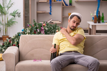 Obraz premium Young man cleaning the apartment after Christmas party