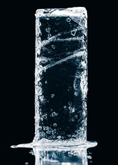 Solid natural ice block with cracks on a black reflective surface. Clipping path included.