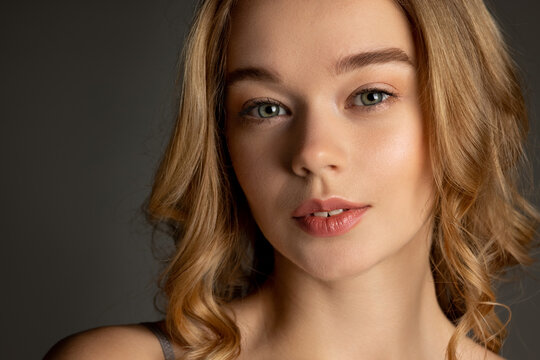 Close-up portrait of young beautiful girl with day makeup isolated over gray studio background. Natural beauty concept.