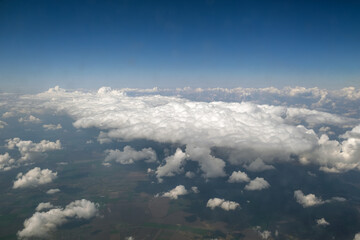 Naklejka na ściany i meble Aerial view from airplane window of white puffy clouds on bright sunny day