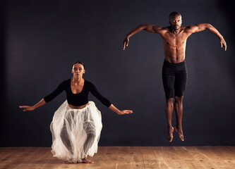 Flight. A female and male contemporary dancer performing a dramatic pose in front of a dark...