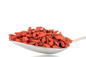 Dried sweet goji berries with a metal spoon, macro, isolated on white.
