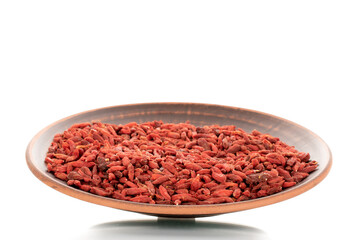 Dried sweet goji berries on a clay dish, macro, isolated on white.