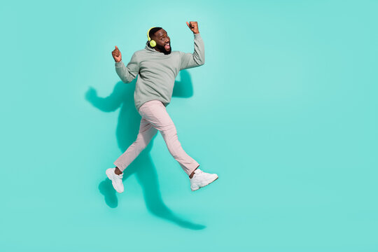 Full length body size view of cheerful handsome trendy guy jumping listening pop isolated over bright teal turquoise color background