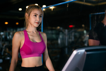 Fototapeta na wymiar couple young women asian and white man walking and running in a gym on a treadmill.exercising concept.fitness healthy lifestyle cinematic dark tone
