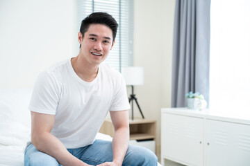 Portrait of Asian active strong man wear pajamas wake up in bedroom. 