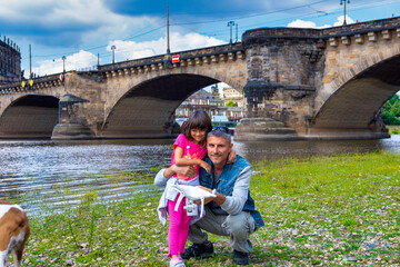 Happy man along the city river with her daughter on a sunny day.