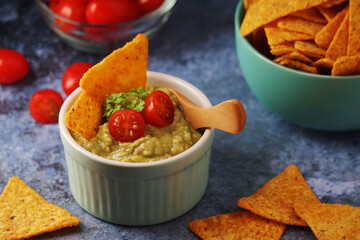 Homemade guacamole with corn chips and cherry tomatoes