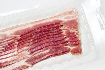 Vacuum-packed bacon on a white background. A modern way of storing and selling meat. Pig meat.