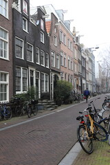 Fototapeta na wymiar Amsterdam Street View with Traditional Houses, Bicycles and Walking Man, Netherlands