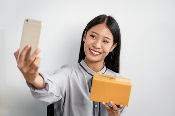 Fototapeta na wymiar Female entrepreneur is selfie with parcel boxes after checking customer order on laptop and packing products