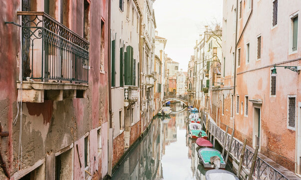 Boats on arrow channel between old colored buildings