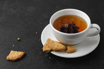 Cup of black tea with cookies on dark background.