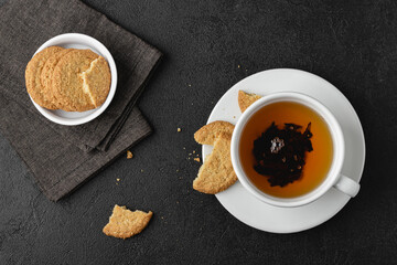 Cup of tea with cookies on black background.