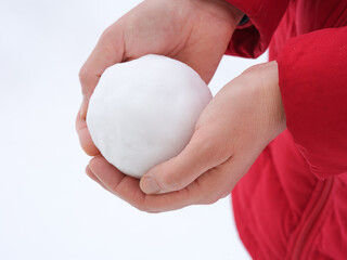 A woman holding a snowball in her hands. Close up.