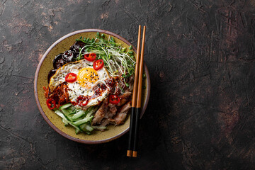Traditional Korean dish Bibimbap. Bowl with rice, shiitake mushrooms, chicken, cucumber and...