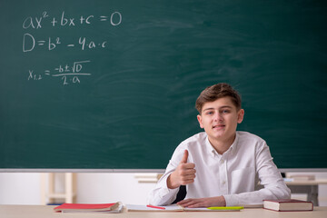 Schoolboy studying math in front of blackboard