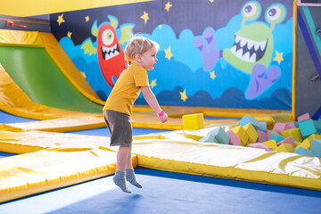 cute blond little boy jumps in a trampoline park, children activity