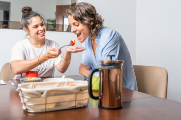 Woman giving food to her lesbian couple in a table at home