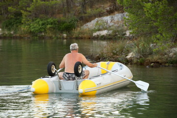 An elderly man approaches the wild shore on a dinghy. A small inflatable rubber boat for landing...