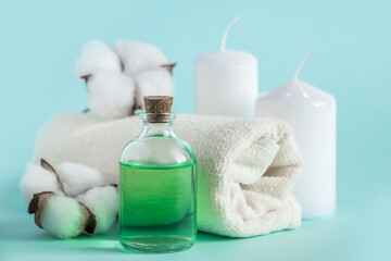 Natural organic beauty products for spa and aromatherapy. Aromatic essential oil, candles and a towel on a blue background. Relaxation concept