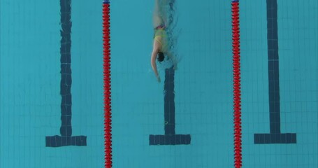 Professional training of an athlete in the pool, preparation for the competition. Swimmer swims in crawl on the water path of the pool, blue water. Woman swimmer in goggles, cap and swimsuit. 4k