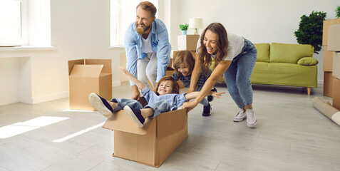 Fototapeta na wymiar Happy excited young family having fun in spacious interior of new home. First-time buyers playing with boxes and laughing. Real estate, residential mortgage, buying house concept. Banner background