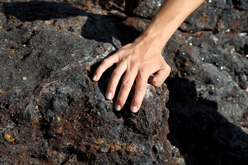 Mano su roccia nera della spiaggia di Terranera, isola d'Elba. Italia - obrazy, fototapety, plakaty