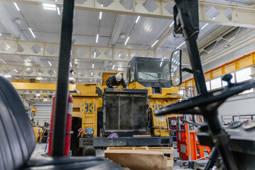 A mechanic fixes a dump truck in an industrial garage. © CjVitoS