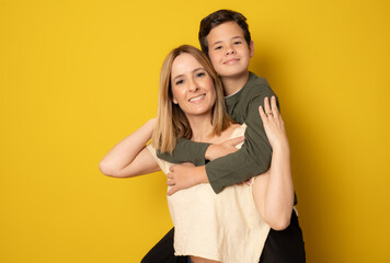 Mother and son in a loving pose isolated on a yellow background.