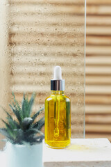Face serum in a glass container against the background of fogged glass in the bathroom. Care for the face and body in the shower. A moisturizing oil for body and face