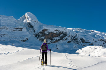 A young girl with snow rackets, walks through a completely snowy landscape in the Pyrenees mountain range (Spain)