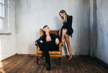 Portrait of Couple two professional ballroom dancers in loft studio on Brown leather sofa. Sport life concept. Passion and emotional dance.