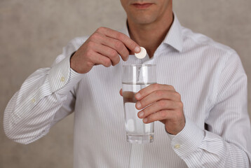 Man holding glass with Vitamin C effervescent tablet close up.