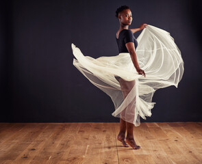 Freedom of movement. Young female contemporary dancer using a soft white white skirt for dramatic...