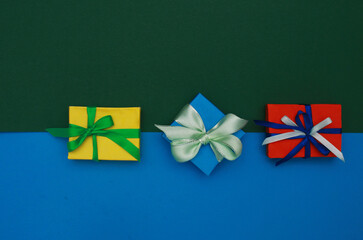 Three colorful gift boxes on blue and green background, top view.