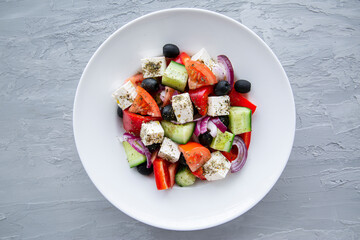 Fresh tasty greek salad on grey stone concrete background, top view. 