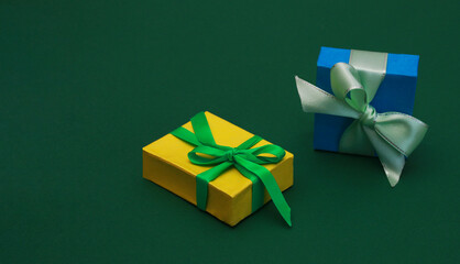 Two Beautiful multicolored gift boxes on green paper background.