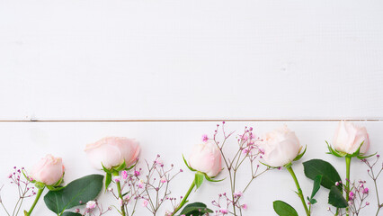 Delicate pink roses and gypsophila on a white wooden background