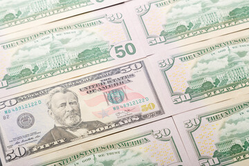 Fifty dollar bills are spread out on the table surface.