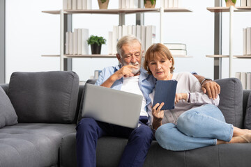 senior couple using laptop computer and tablet on sofa