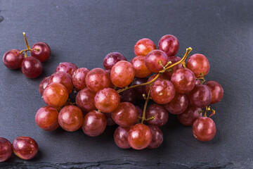 Close up view of bunch of grapes  isolated on black cutting board.