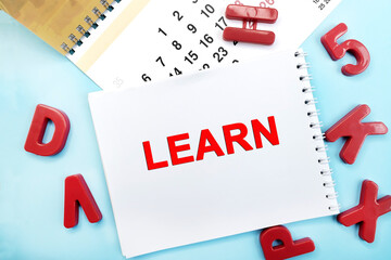 Notepad with the inscription study on a blue background with a calendar and red plastic numbers. Learning concept