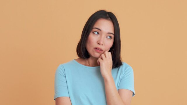 Bored woman in blue t-shirt agree with something in the beige studio