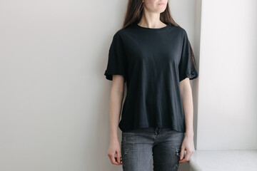 Woman wearing black blank t-shirt with space for your logo, mock up or design indoors